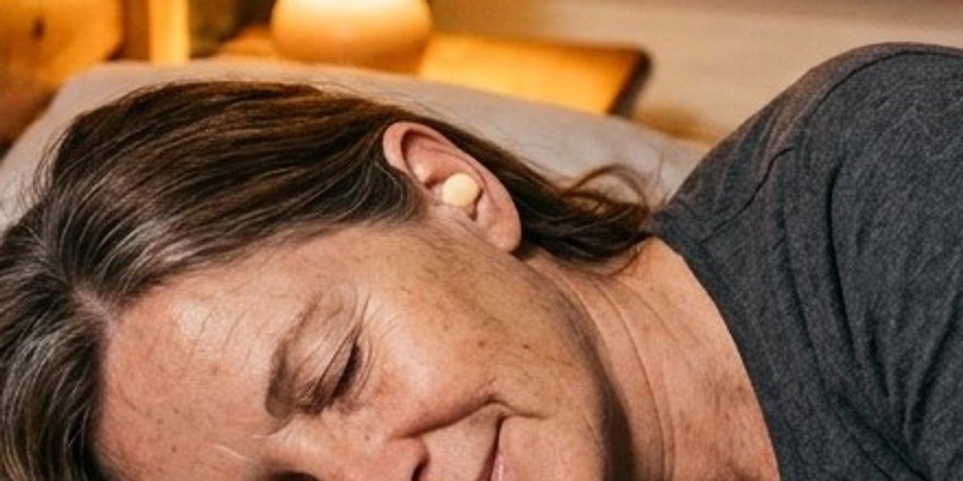 Close-up of a beige foam earplug sitting snugly in a sleeping pilgrim&rsquo;s ear