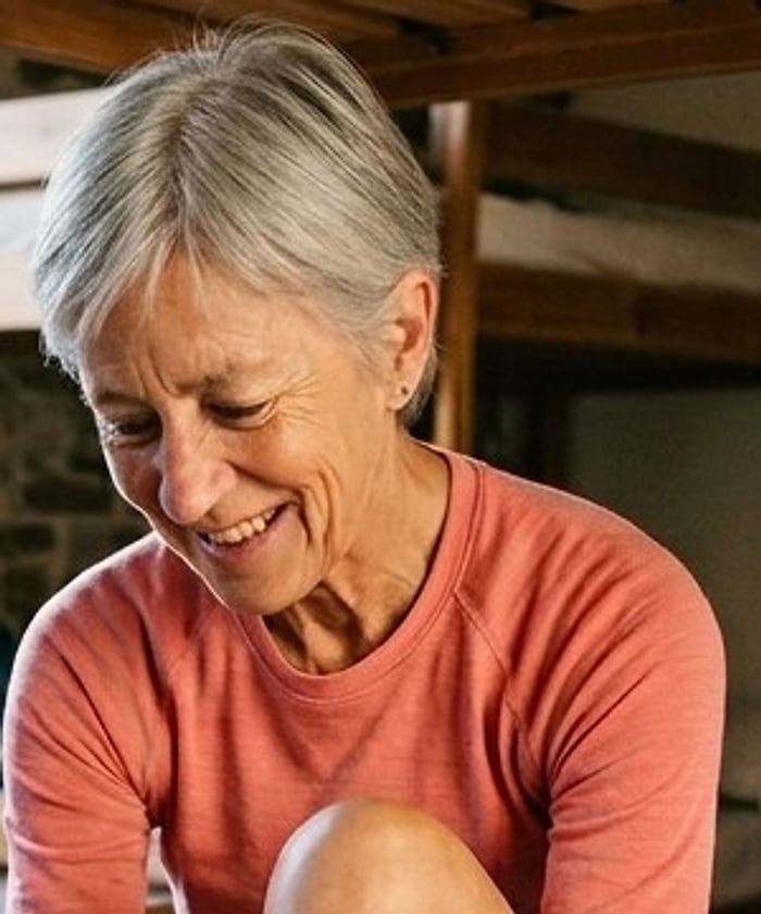 A pilgrim with short silver hair smiling down at her feet